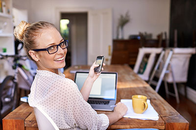 Une femme prend des notes sur son téléphone alors qu'elle est assise au bureau.