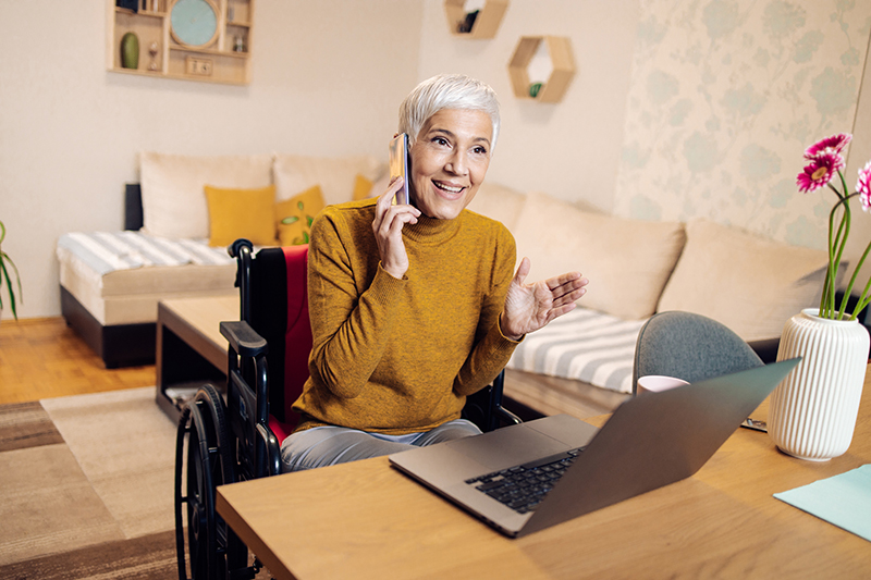 Femme mûre en fauteuil roulant travaillant à domicile et passant des appels professionnels